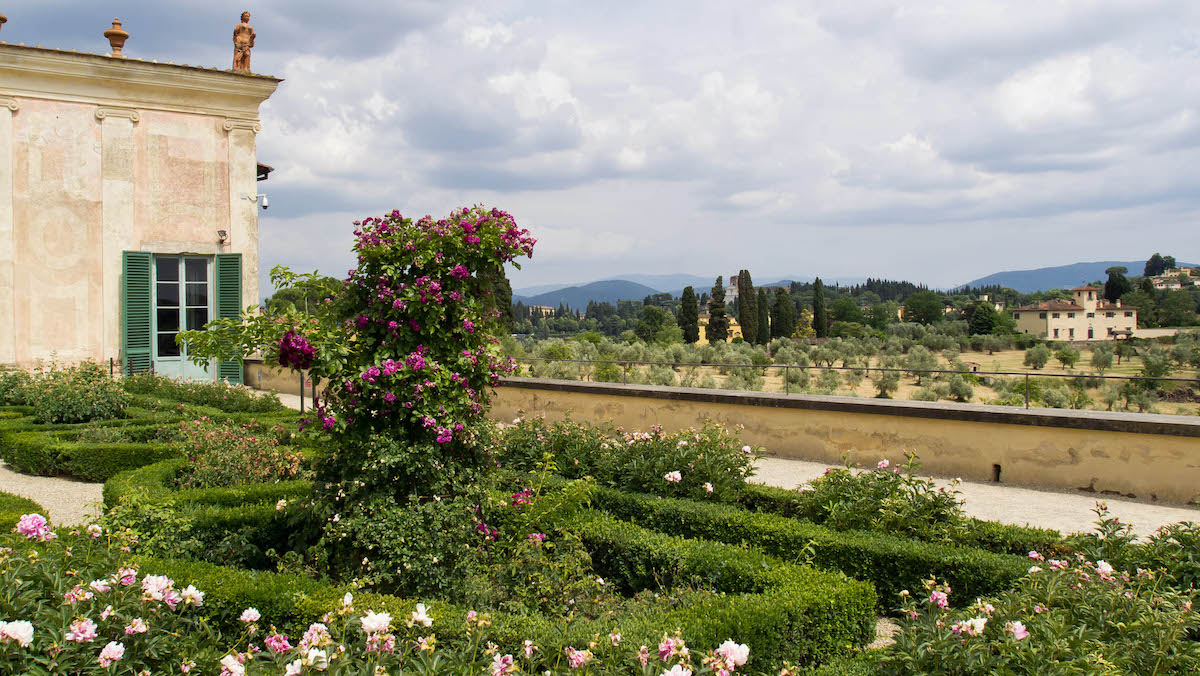 Jardines en una villa italiana con un pequeño edificio marrón al fondo