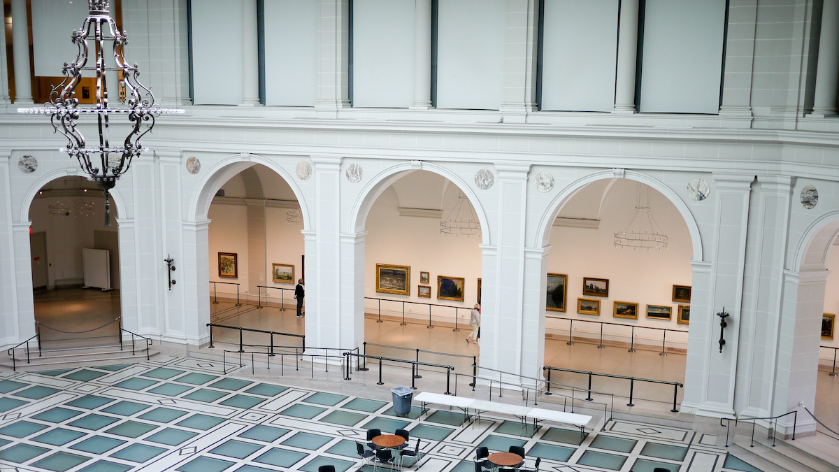 El interior de un museo de arte con pisos de baldosas verde azulado, lámparas y arcos