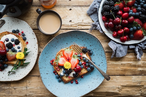 Tostadas francesas en un plato con bayas frescas y una taza de café