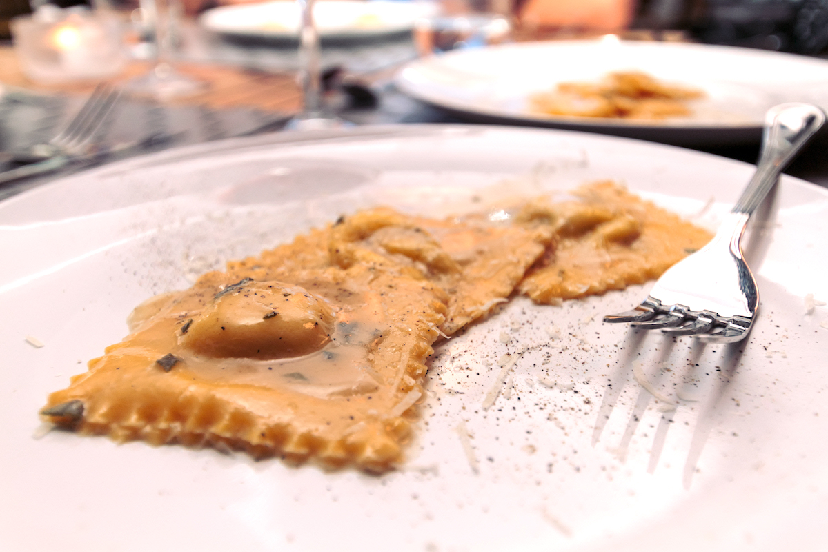 Tres ravioles cerca de un tenedor en un plato blanco