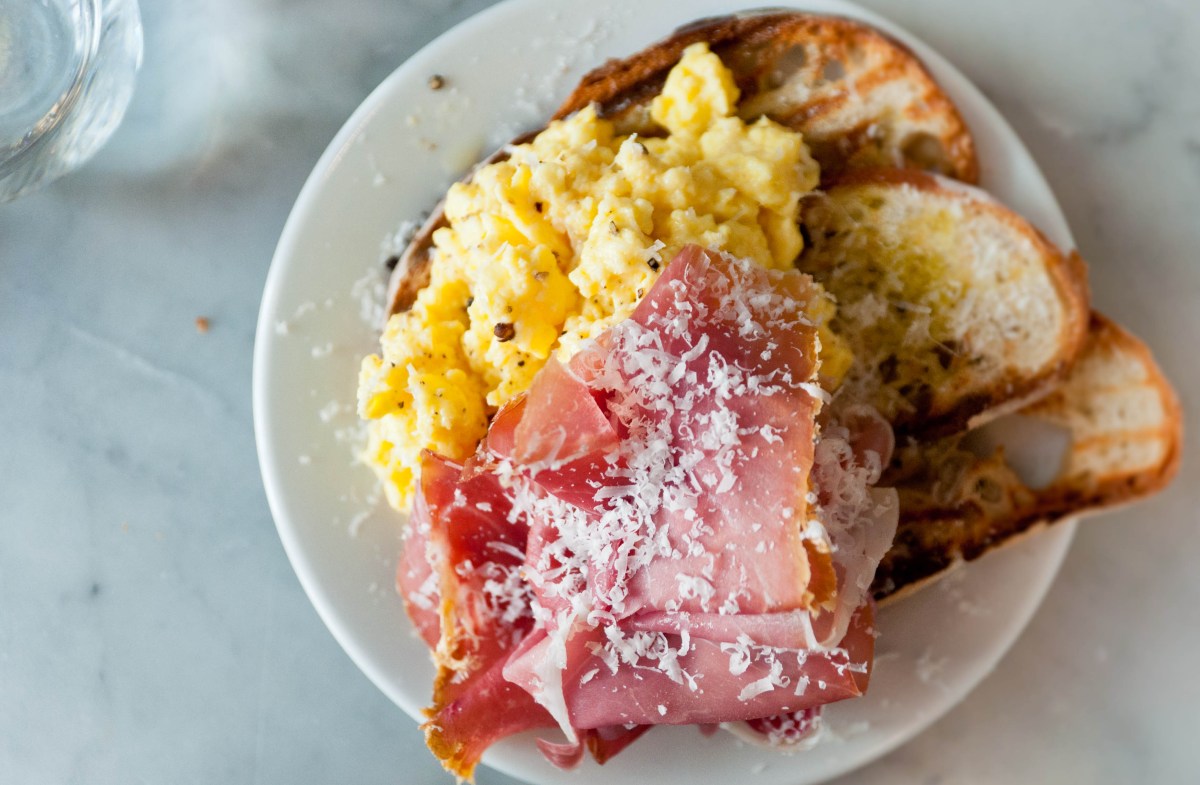 Fotografía cenital de embutidos, huevos revueltos y tostadas en un plato blanco