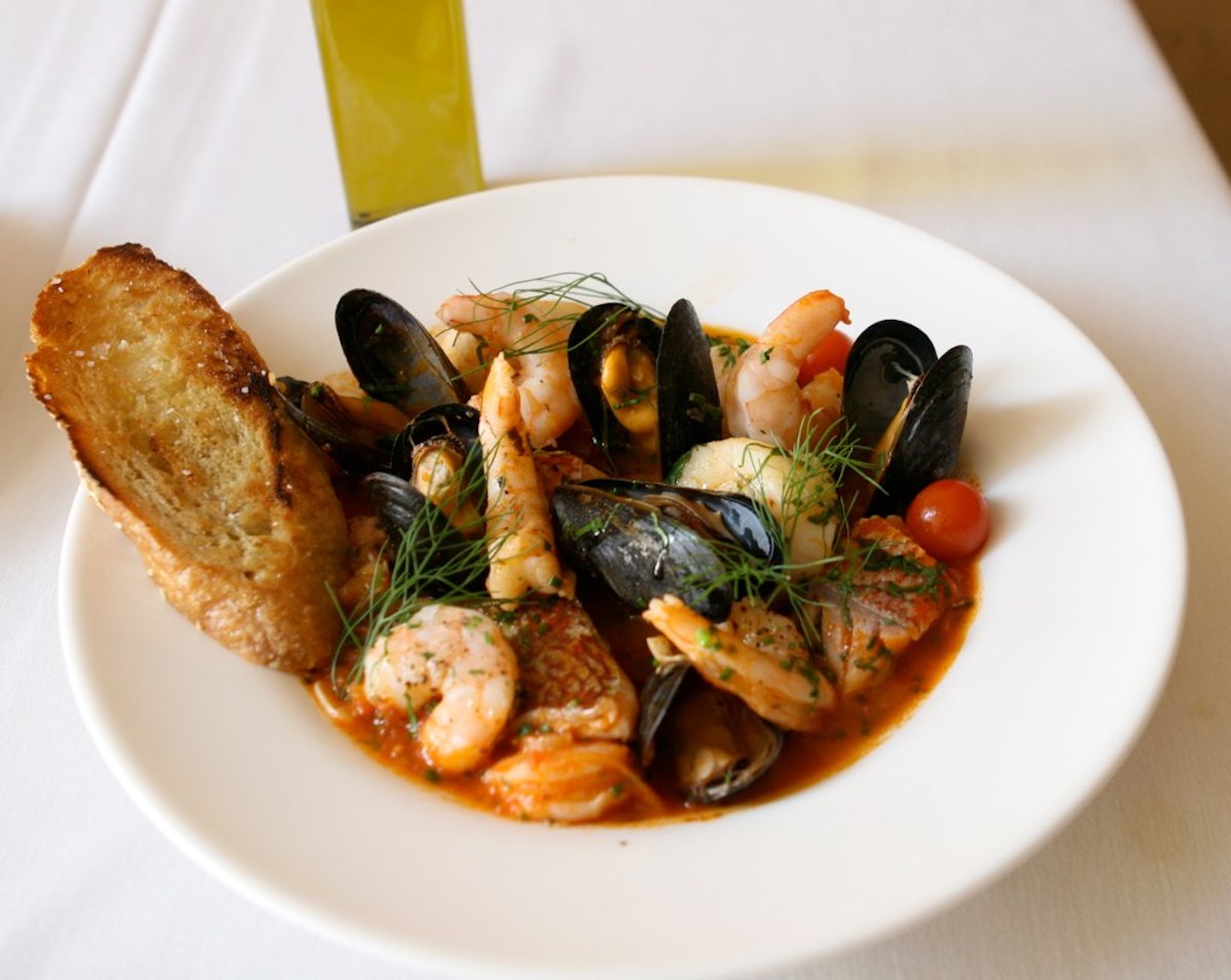 Guiso de mariscos con gambas, mejillones y pescado en caldo de tomate espolvoreado con hierbas frescas