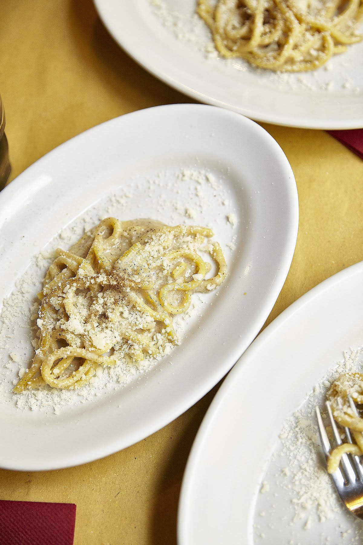 Fotografía cenital de pasta cacio e pepe en un plato blanco de forma ovalada