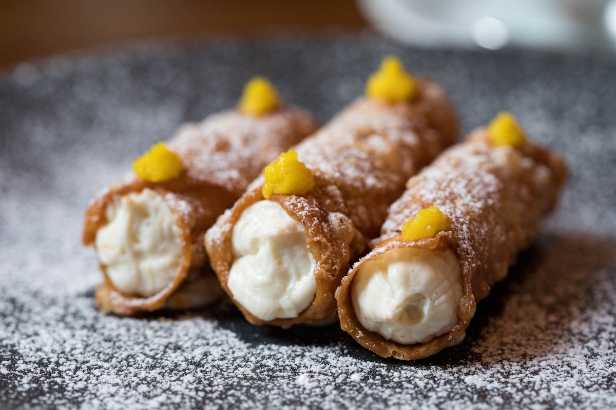 Tres cannoli en un plato espolvoreado con azúcar en polvo