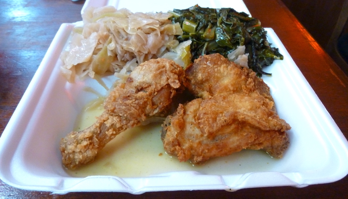 Pollo frito y col rizada servidos en una caja de espuma de poliestireno