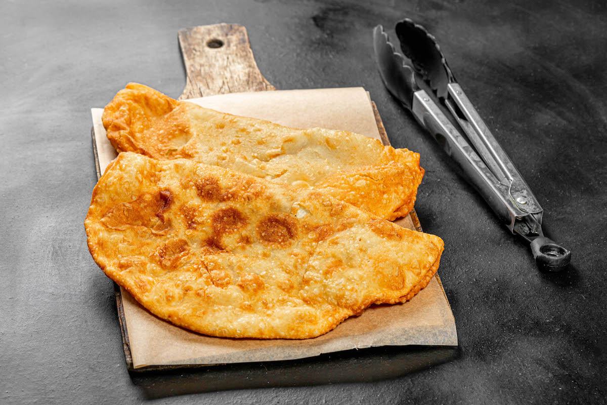 Dos empanadas fritas en una tabla de cortar de madera