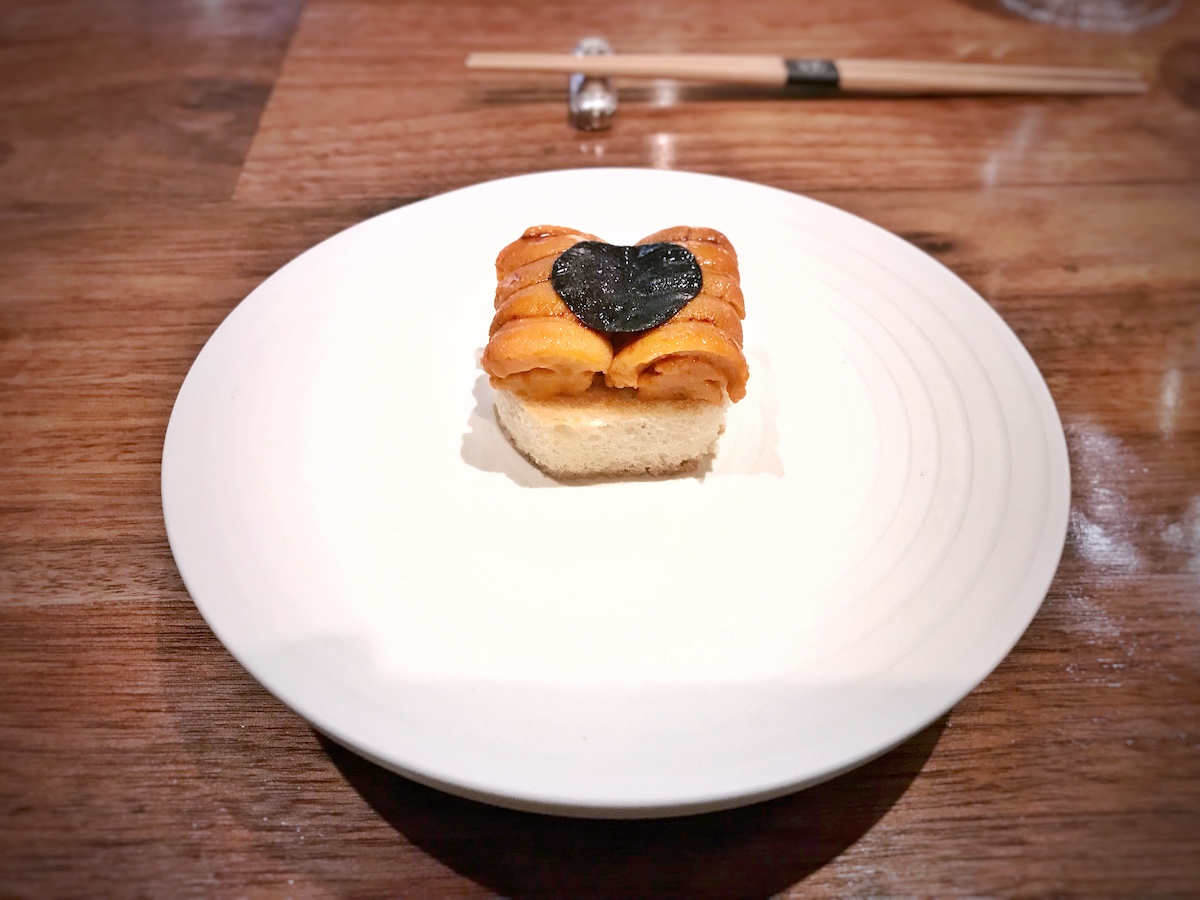 Hokkaido uni, trufa negra y brioche servidos en un plato blanco.