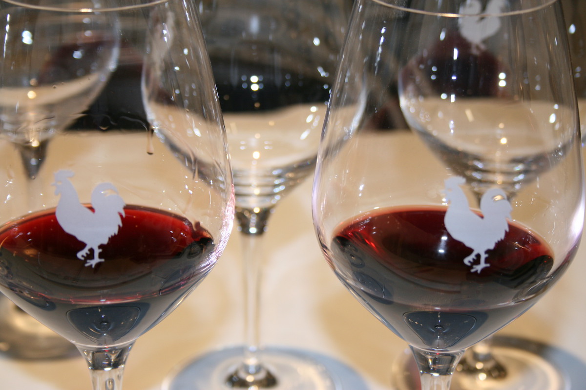 Vino tinto en dos copas decoradas con un símbolo de gallo