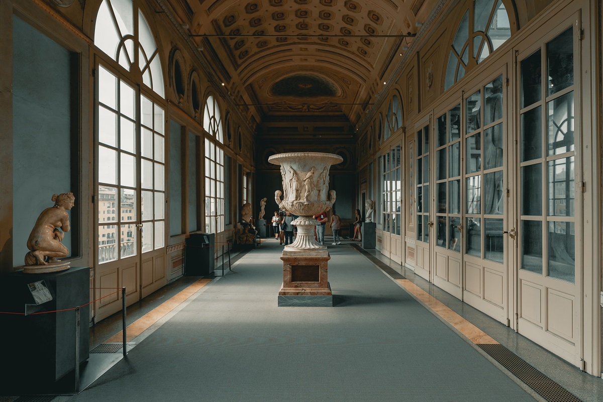 Un salón elegante con paredes curvas, ventanas altas y una estatua de mármol en el centro.