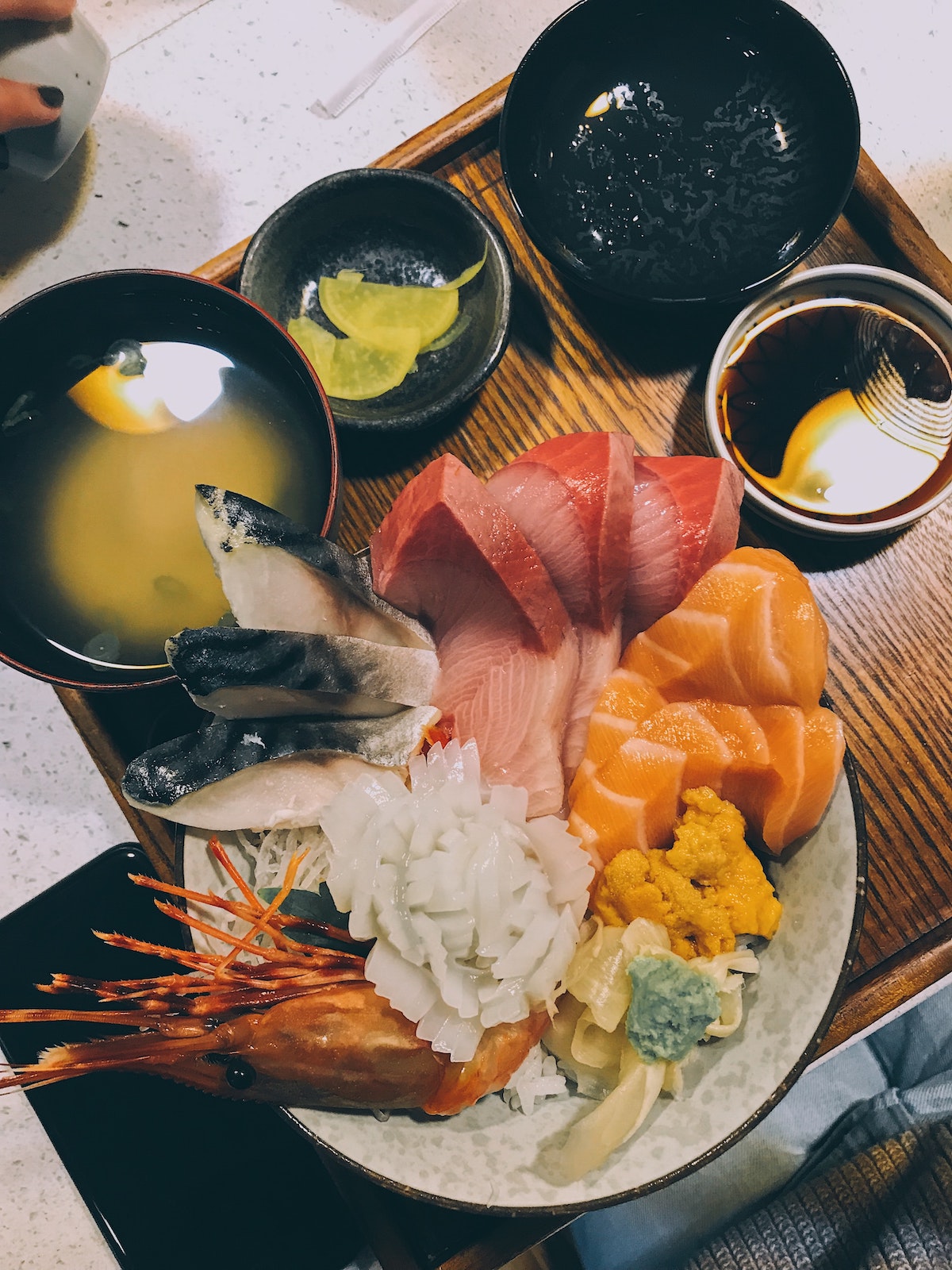 un tazón lleno de arroz blanco y una variedad de pescado crudo con varios tazones más pequeños de salsas y sopas en el restaurante Chinatown de Boston