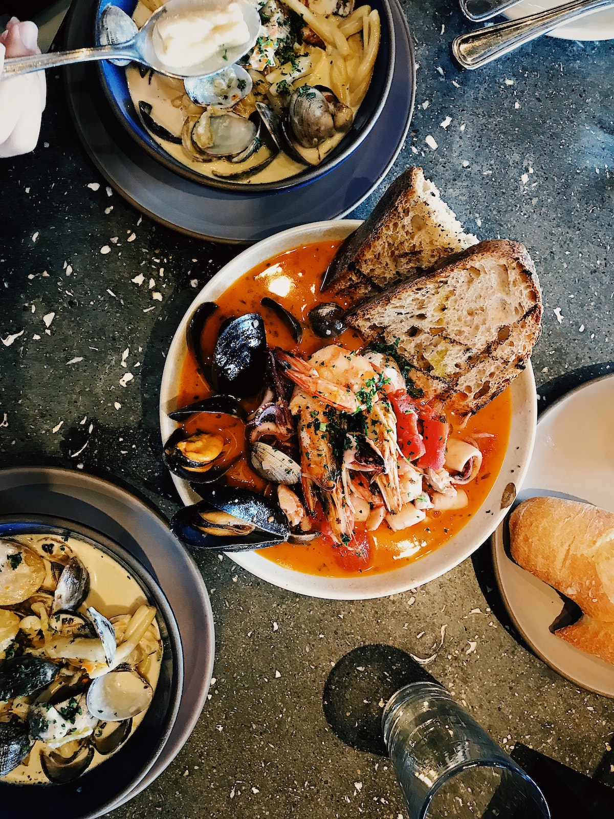 Flatlay de mesas negras con tres tazones grandes de estofado de mariscos