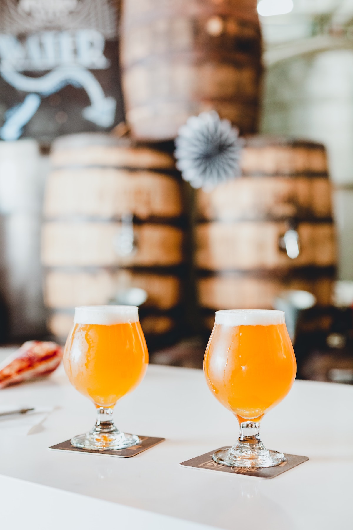 Dos cervezas de colores claros encima de una mesa blanca