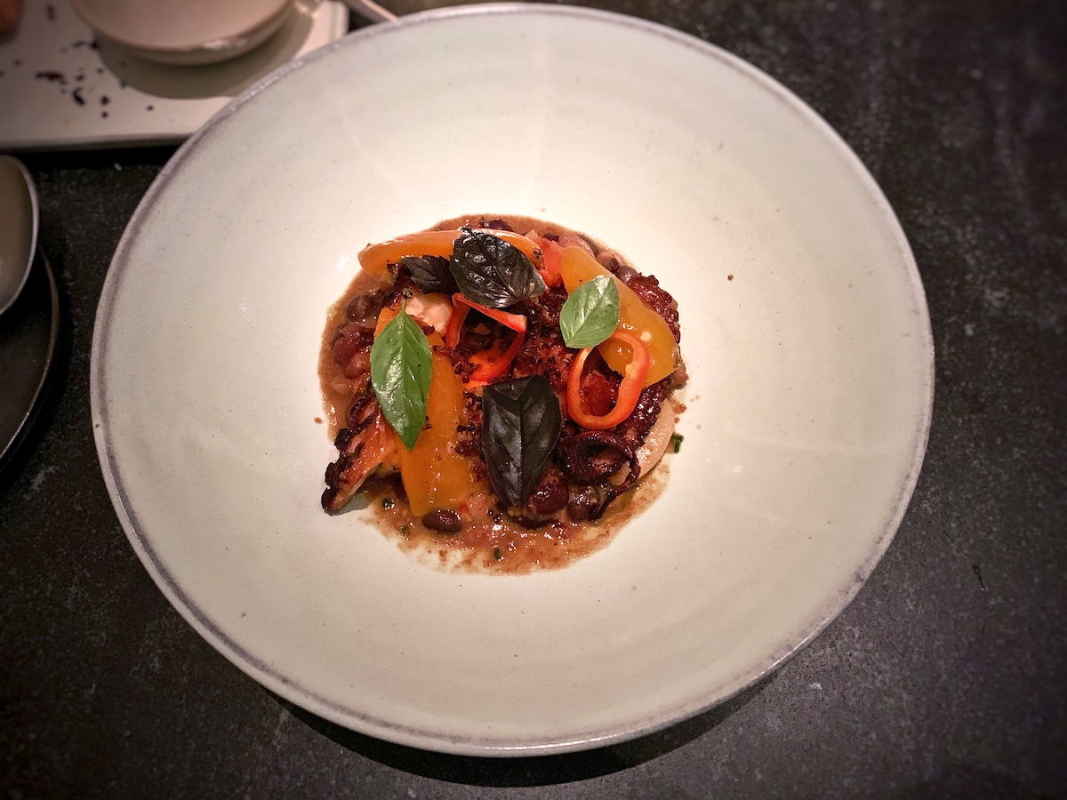 Vista superior de pulpo asado con chorizo ​​y pimientos servido en un restaurante Michelin en Nueva York.