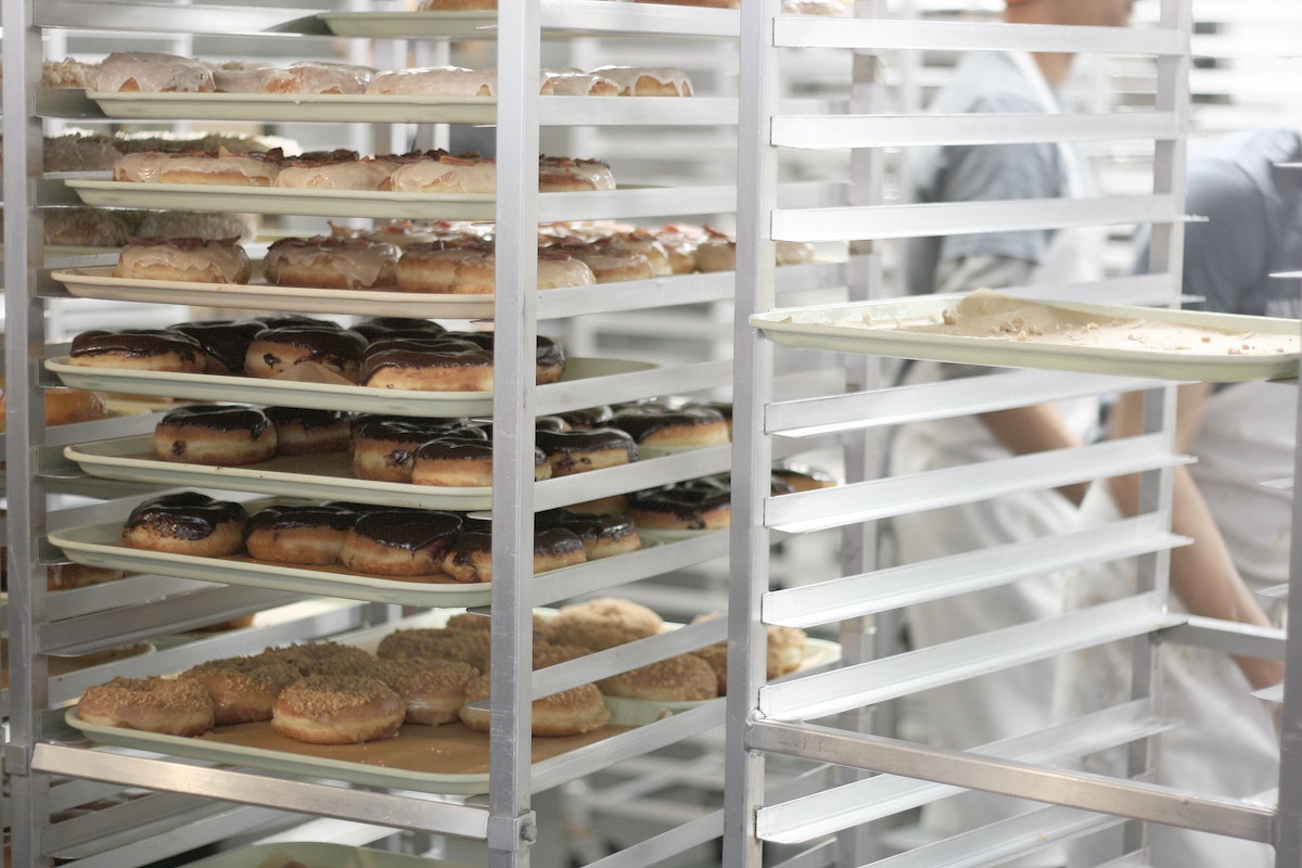 Una rejilla alta de bandejas para hornear llenas de donas