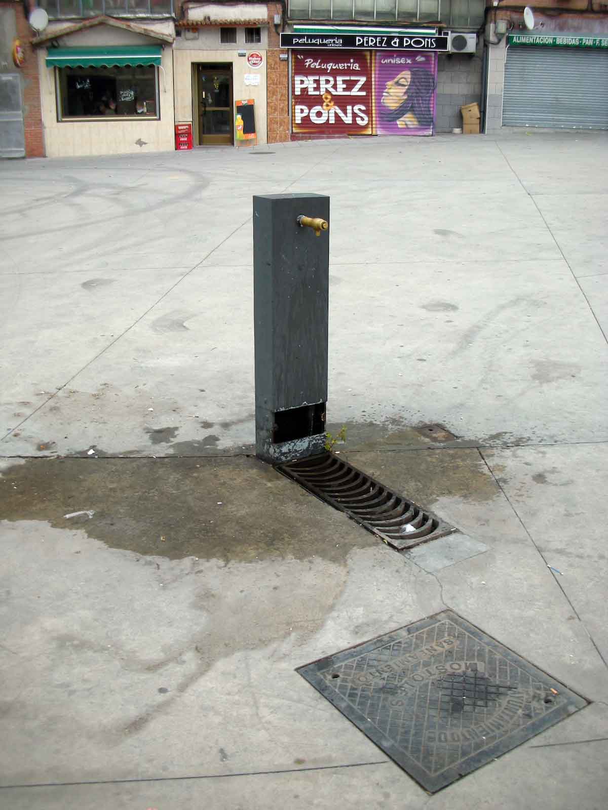 Una fuente de agua potable de piedra rectangular en la acera