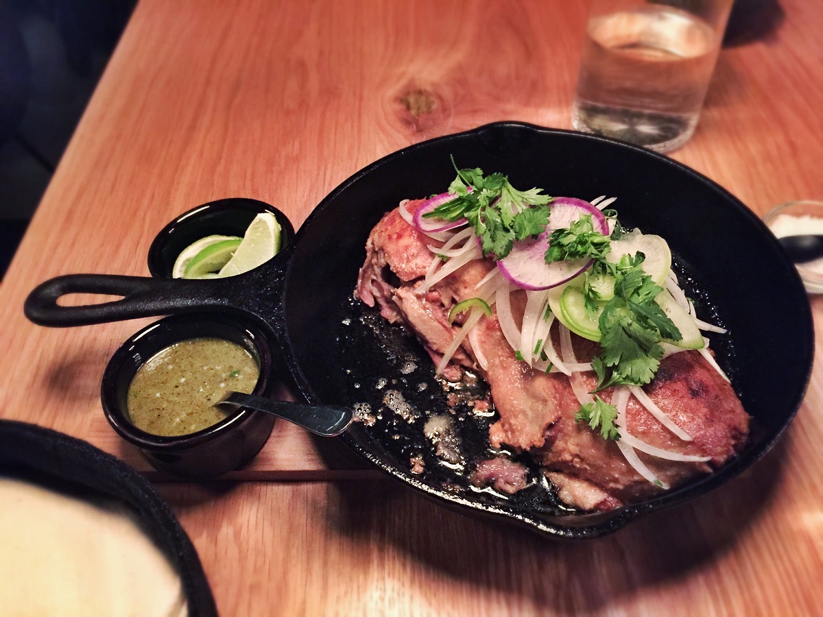 Carnitas de pato en sartén de hierro fundido con cilantro, rábano y cebolla