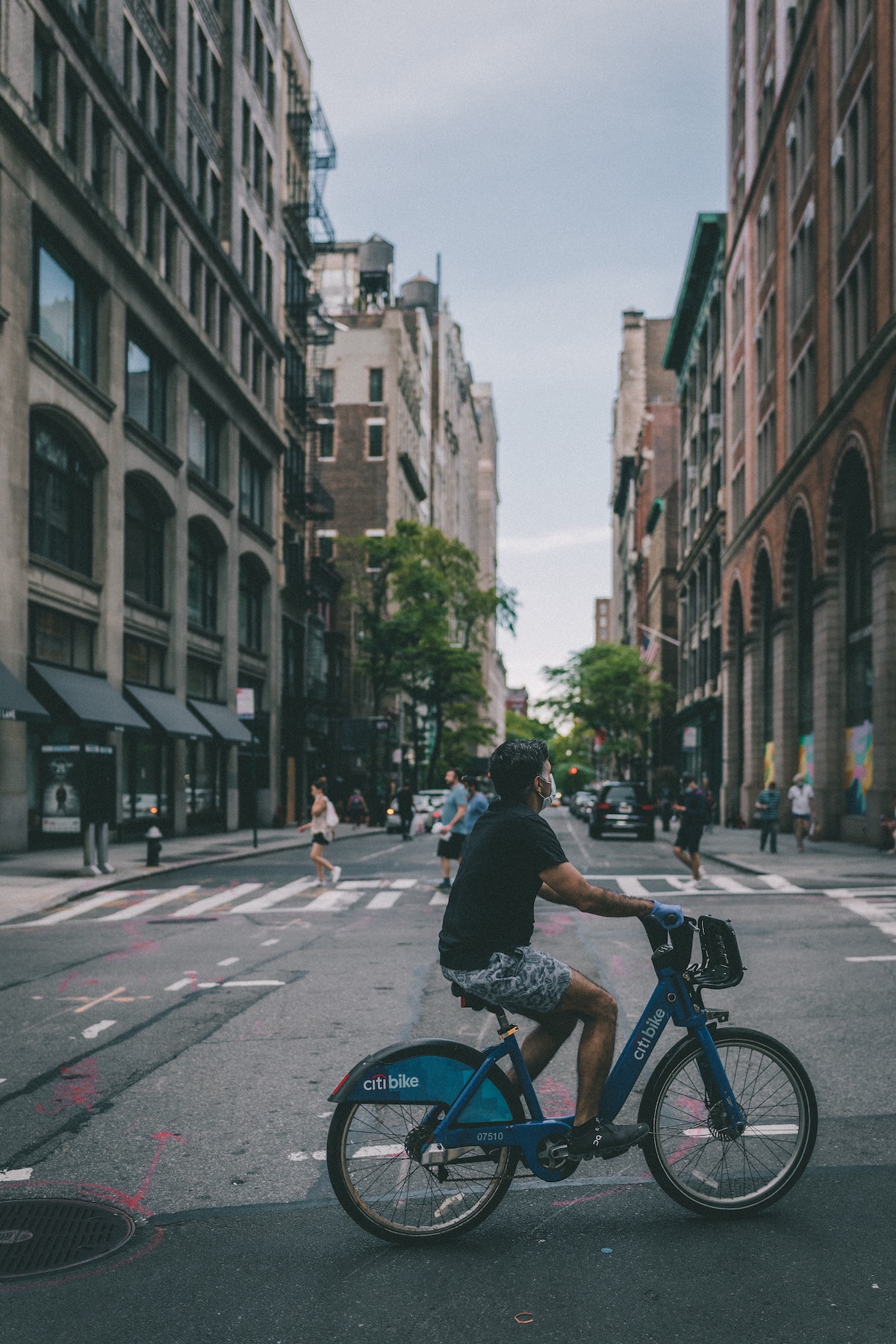 Un hombre vestido con pantalones cortos y una camiseta negra montando en bicicleta en una calle de la ciudad