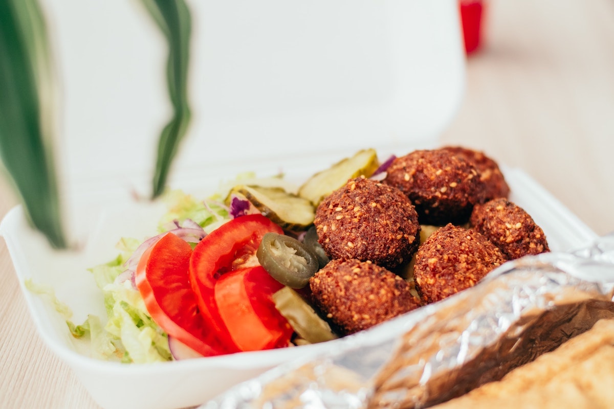 Bolas de falafel, lechuga, pepinillos, cebollas y jalapeños en un plato de espuma de poliestireno
