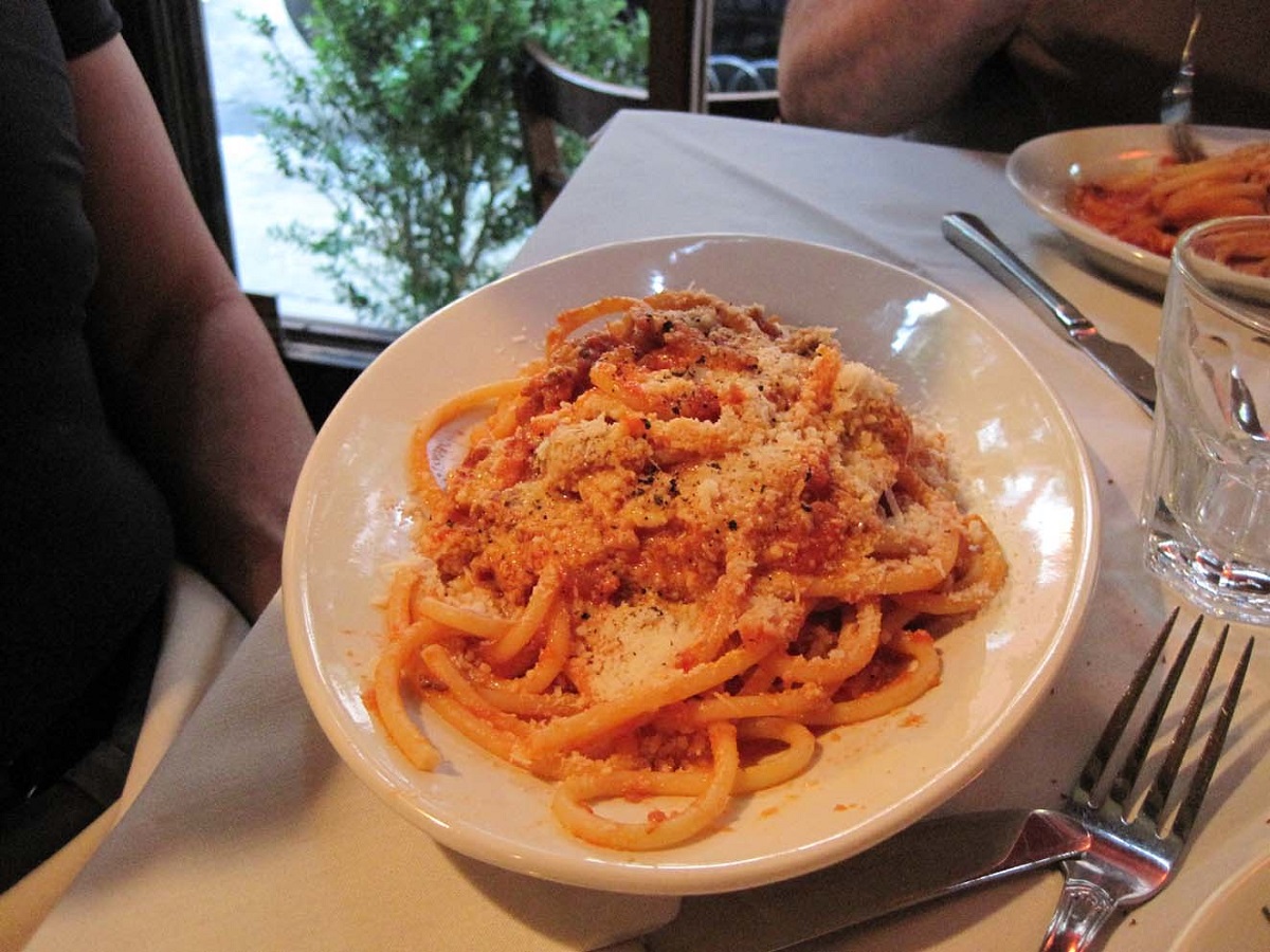 Un plato de espaguetis con salsa de pasta roja y queso parmesano rallado en un restaurante