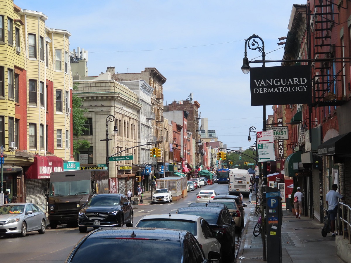 Una calle muy transitada en Brooklyn con fachadas antiguas y tarjetas modernas