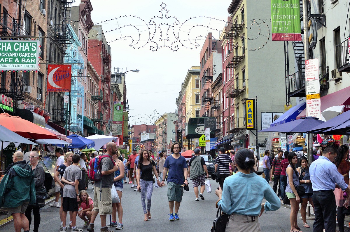 Una pareja camina por una concurrida calle de Nueva York rodeada de farolas, tiendas y otros peatones
