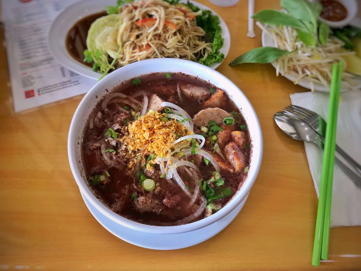 Un tazón de sopa de curry marrón con fideos en una mesa en un restaurante