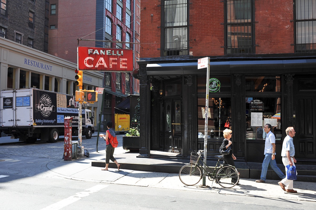 Afuera del restaurante con un letrero que dice Fanelli Cafe con peatones en primer plano
