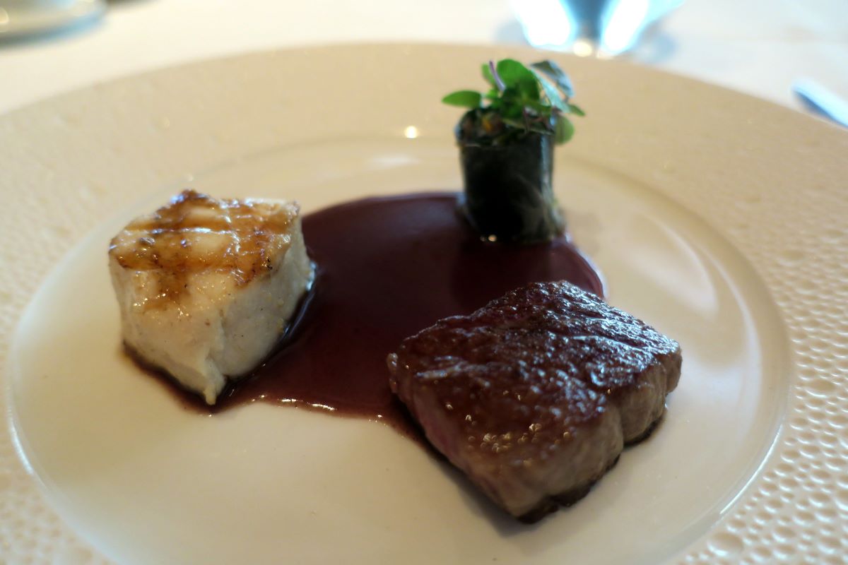 Un plato decadente de carne y patatas en un plato blanco.