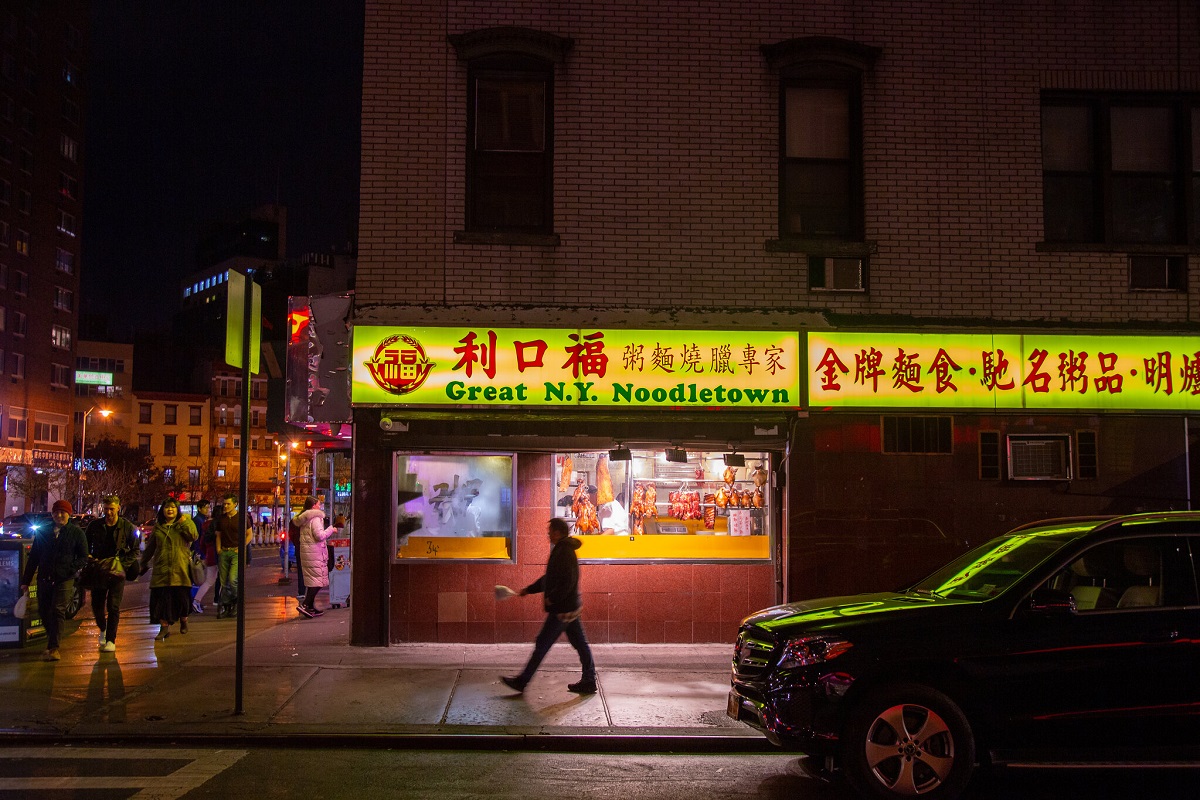 Un hombre camina fuera de un restaurante chino en el barrio chino de Manhattan por la noche