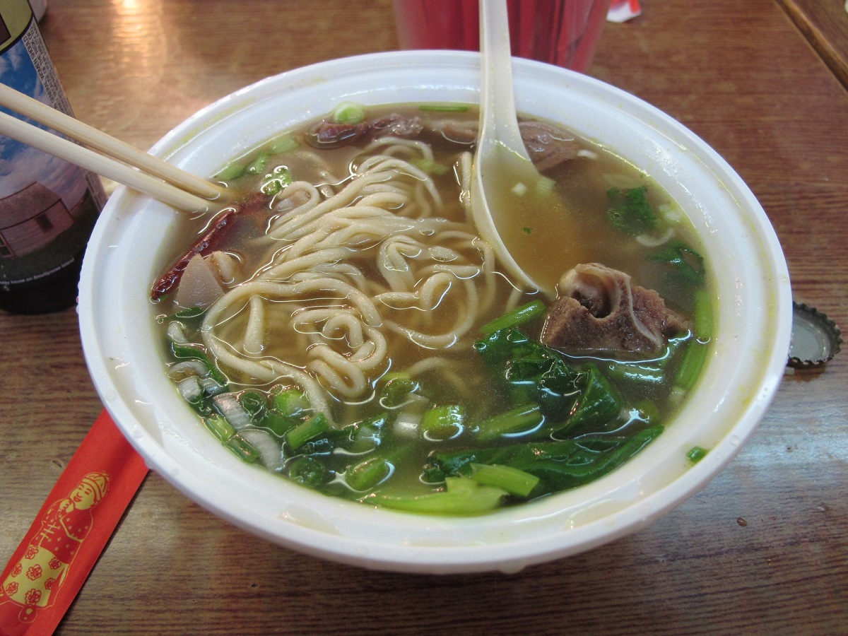 Un tazón grande de sopa con carne de res, verduras y fideos chinos hechos a mano