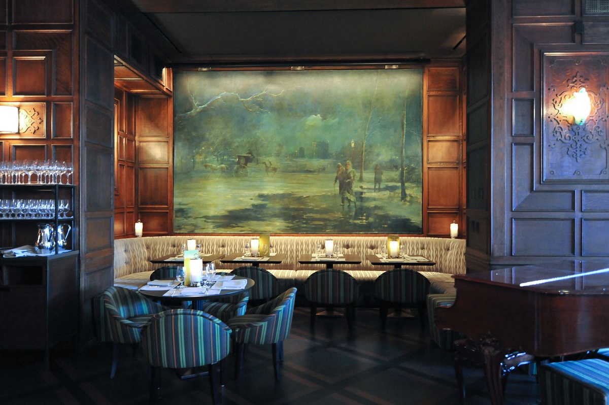 Bar y restaurante con paneles de madera y mesas de comedor con un gran cuadro en la pared