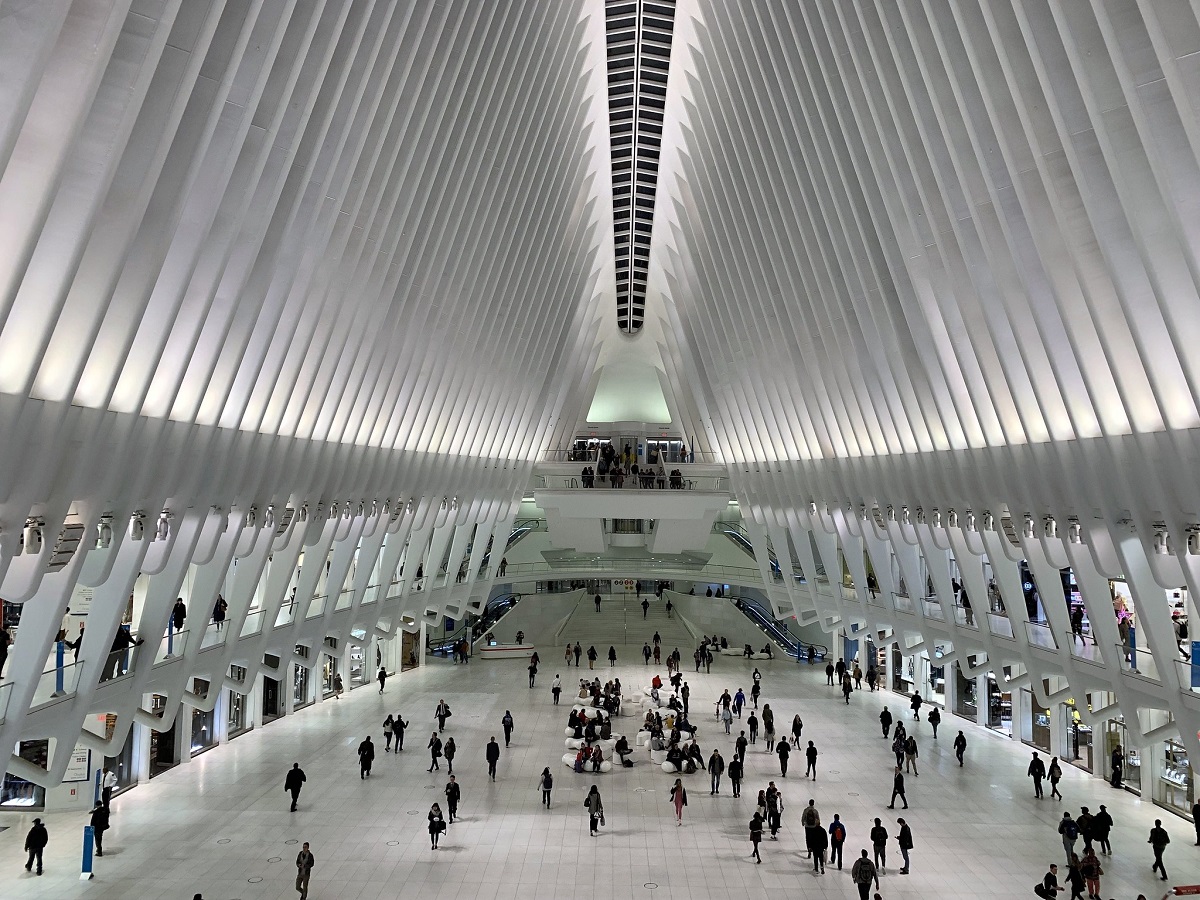 Una estructura triangular blanca con tiendas y gente.
