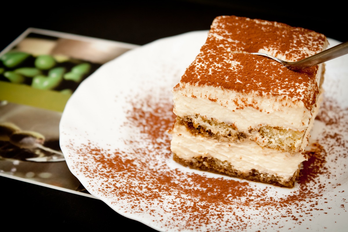 Un plato pequeño con una rebanada de pastel de tiramisú y canela.