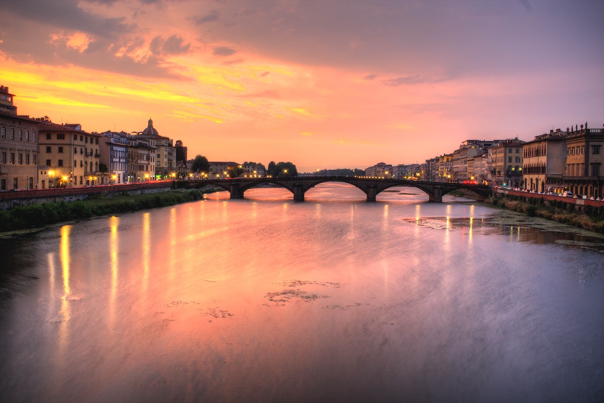 Puesta de sol sobre el río Arno en Florencia con un puente al fondo