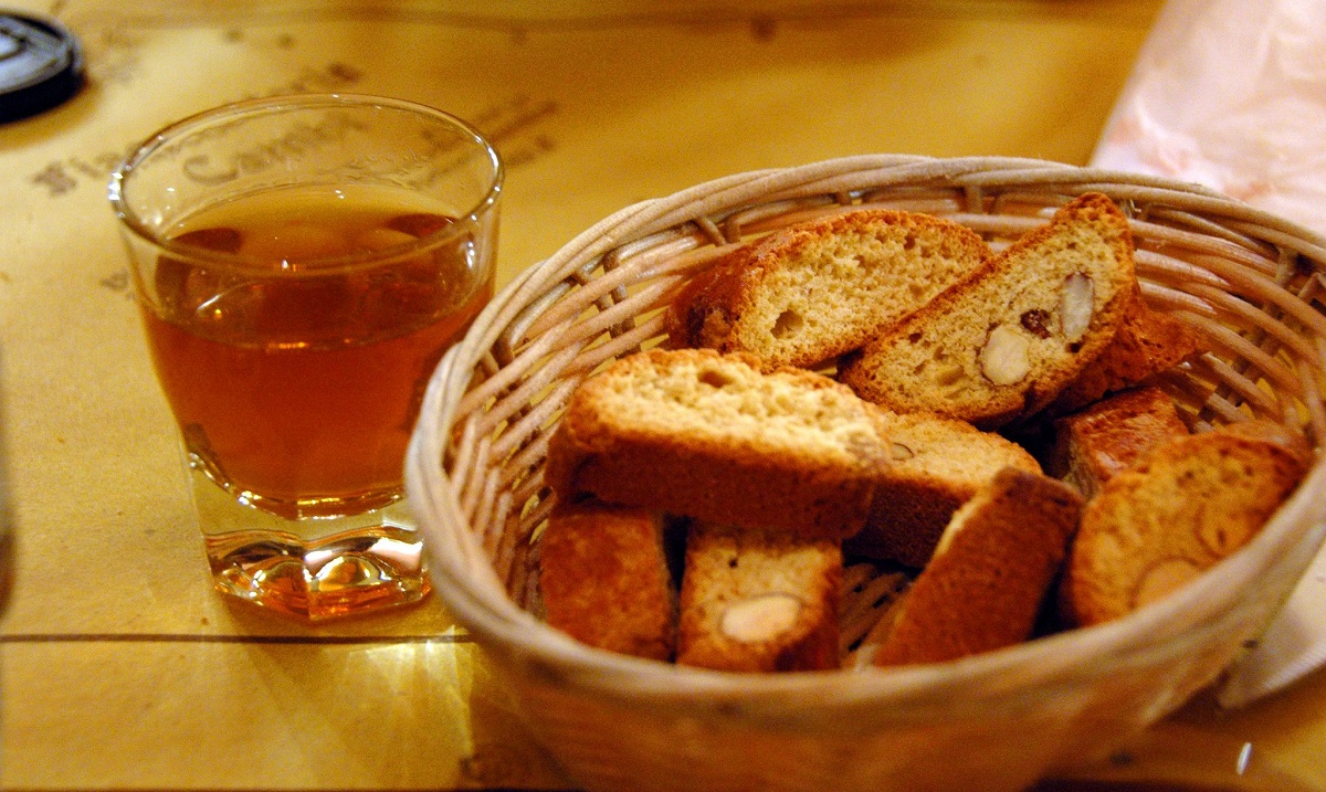 Una canasta de galletas amarillas duras y un vaso pequeño de líquido ámbar