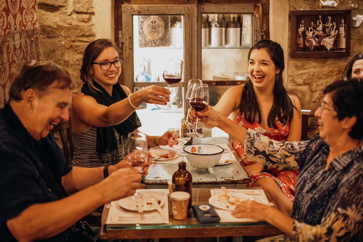 Un grupo de personas brindando con vino tinto alrededor de una mesa