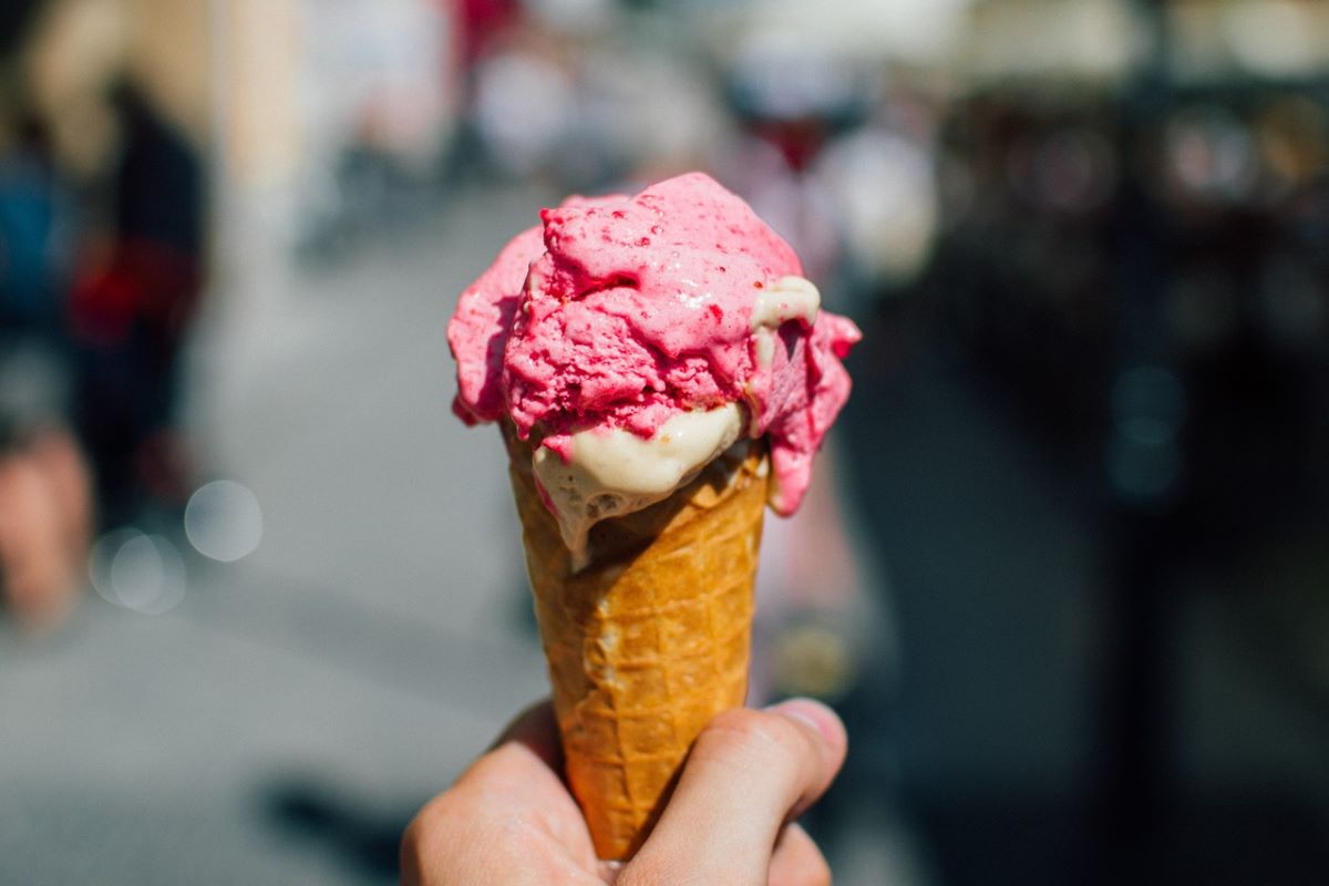 un cono de helado rosa con un fondo urbano