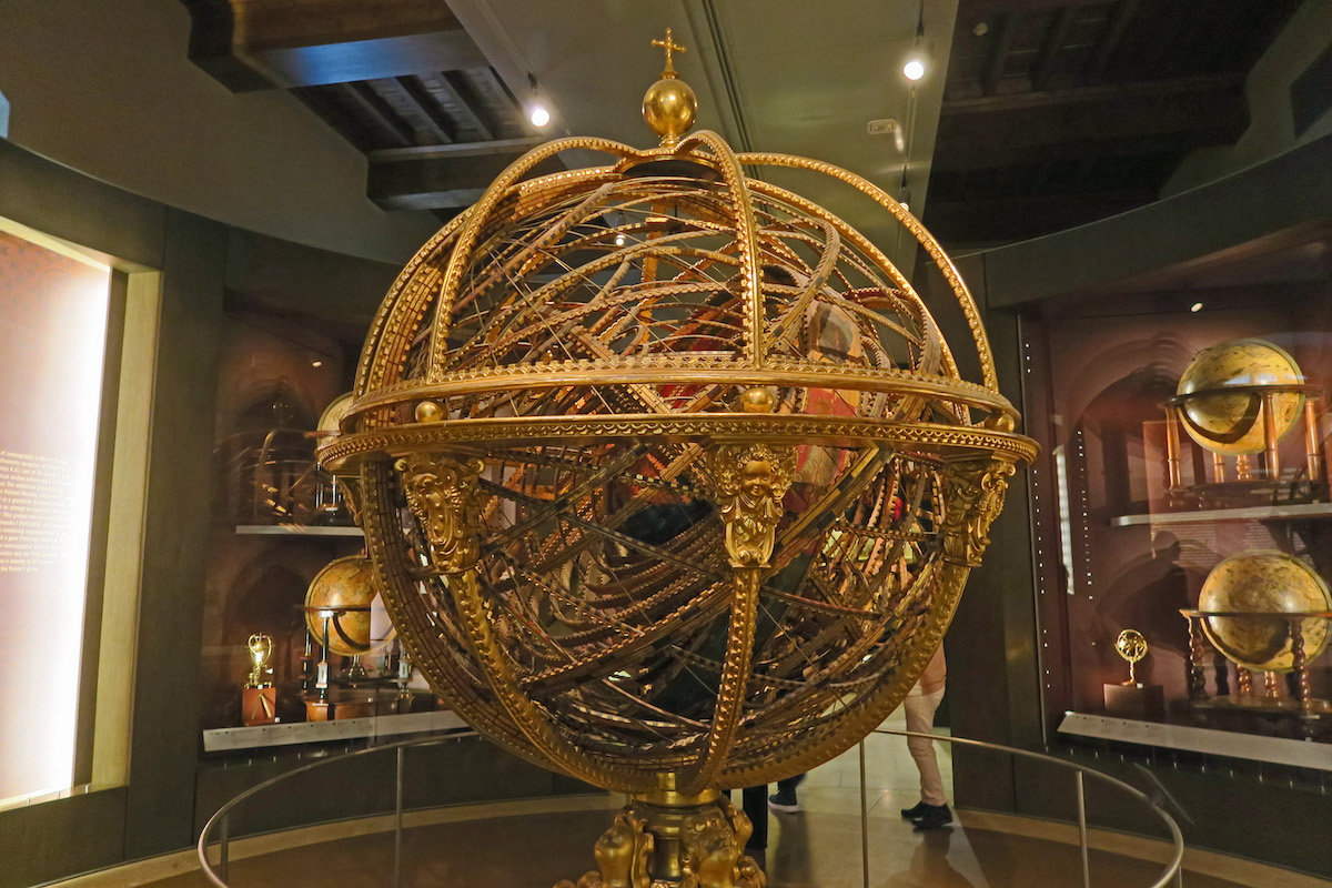 Una gran esfera de metal con intrincados detalles dorados en exhibición en un museo