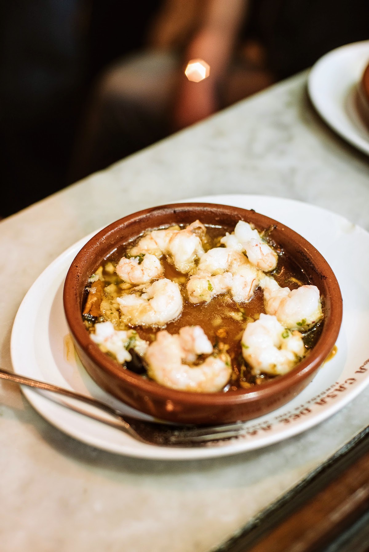 Camarones al ajillo en un plato pequeño de barro.