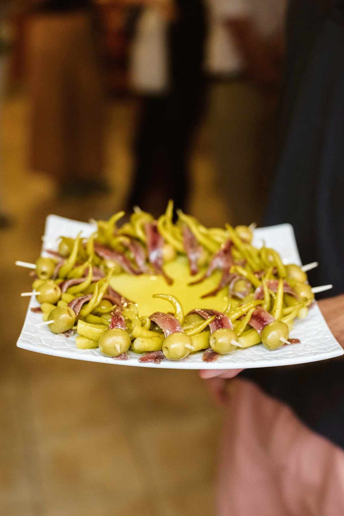 Coloque las brochetas de aceitunas, las anchoas y la pimienta en un plato cuadrado alrededor del aceite. aceituna