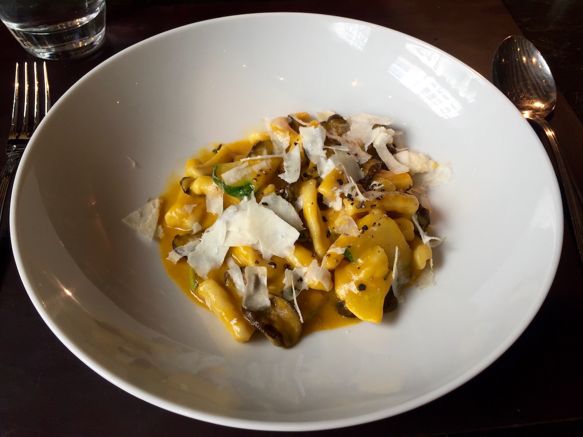 Un plato de pasta con champiñones y queso parmesano afeitado