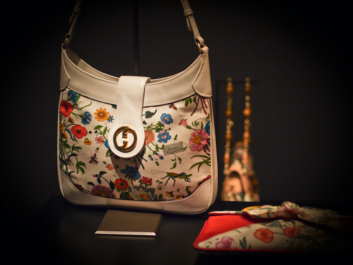 Un bolso y una cartera con estampado floral de Gucci sobre un fondo negro