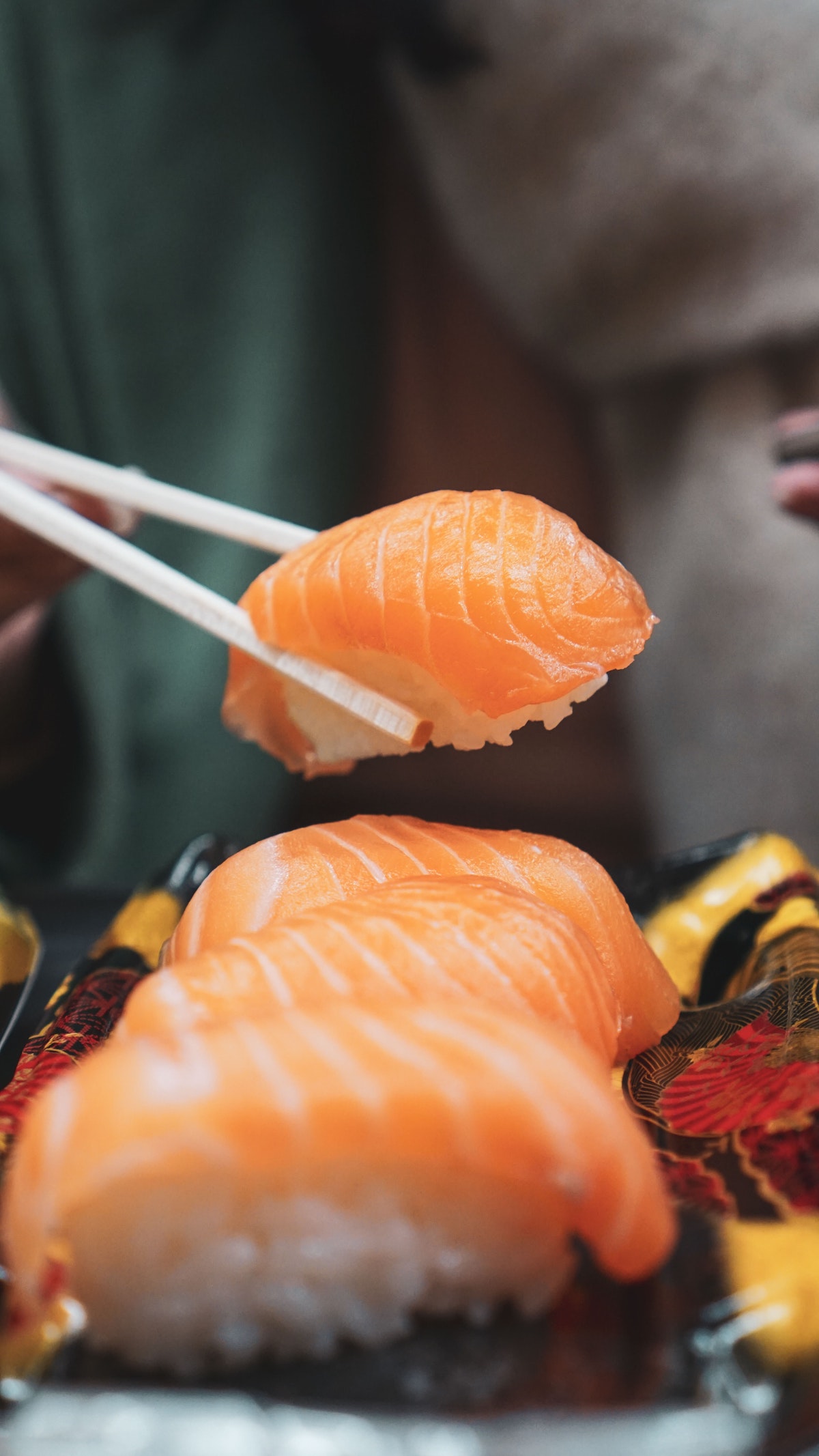 primer plano de una persona recogiendo un rollo de sushi con palillos