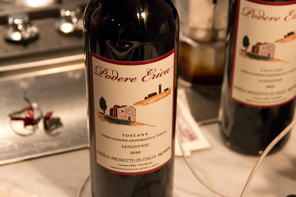 Una botella de vino italiano con una etiqueta que representa una finca toscana