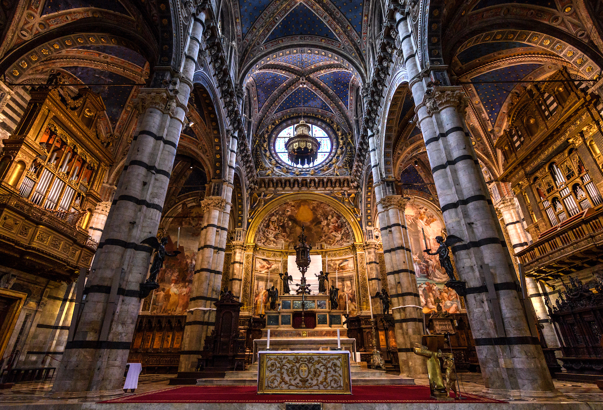 Interior de la catedral gótica con pinturas religiosas y detalles intrincados