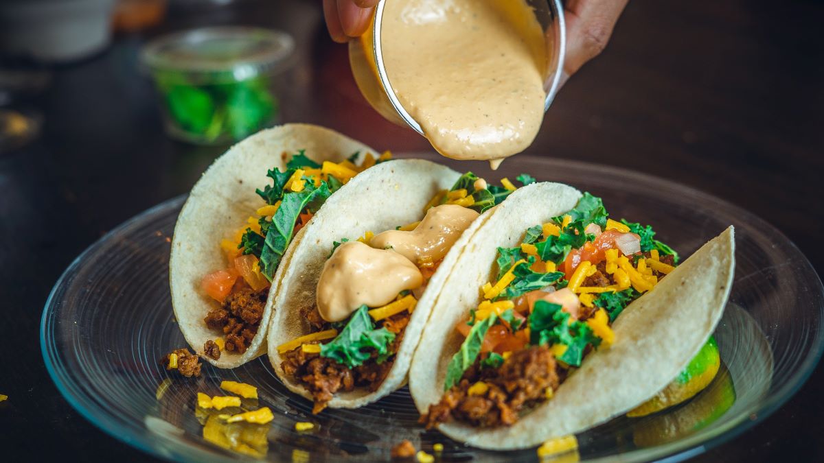 tacos en un plato transparente con salsa vertida a mano 