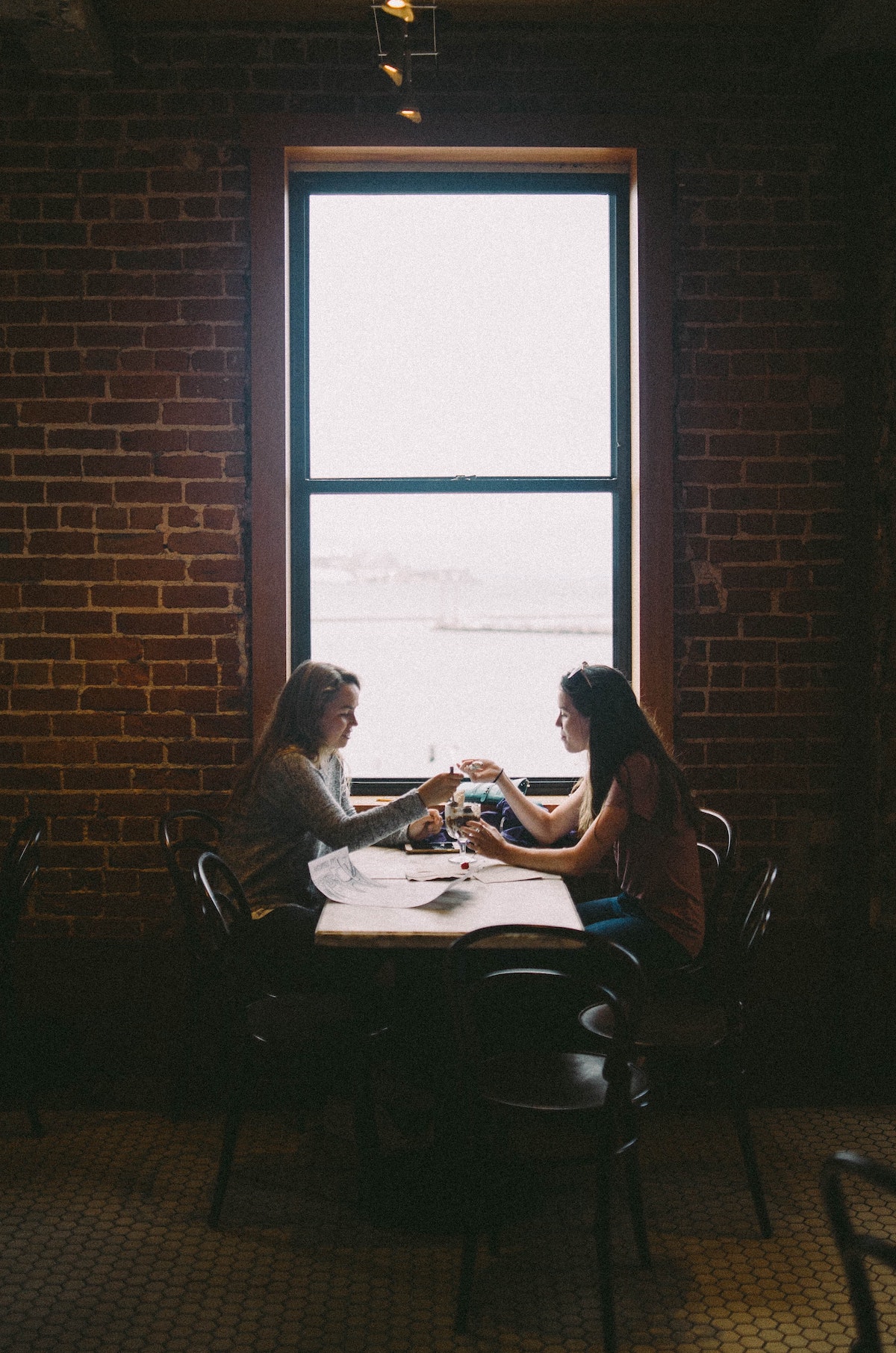Dos mujeres se sientan en una mesa junto a una ventana y comparten un helado en Ghirardelli Square, un famoso restaurante en San Francisco.