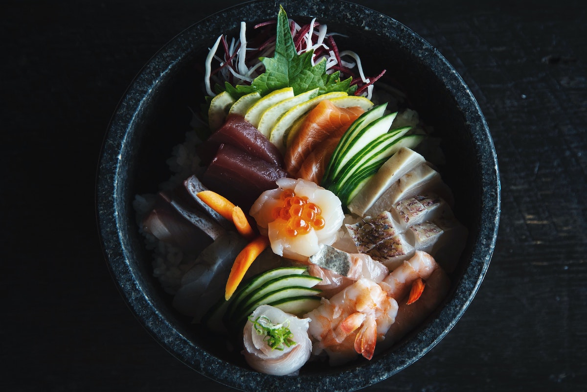 Un tazón negro encima de una mesa negra llena de ingredientes de sushi