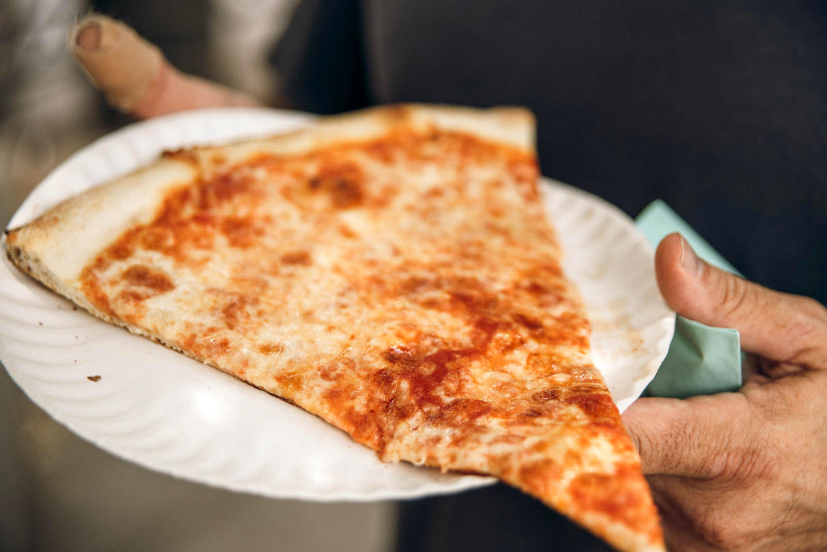 Una gran porción de pizza al estilo de Nueva York en un plato de papel blanco.