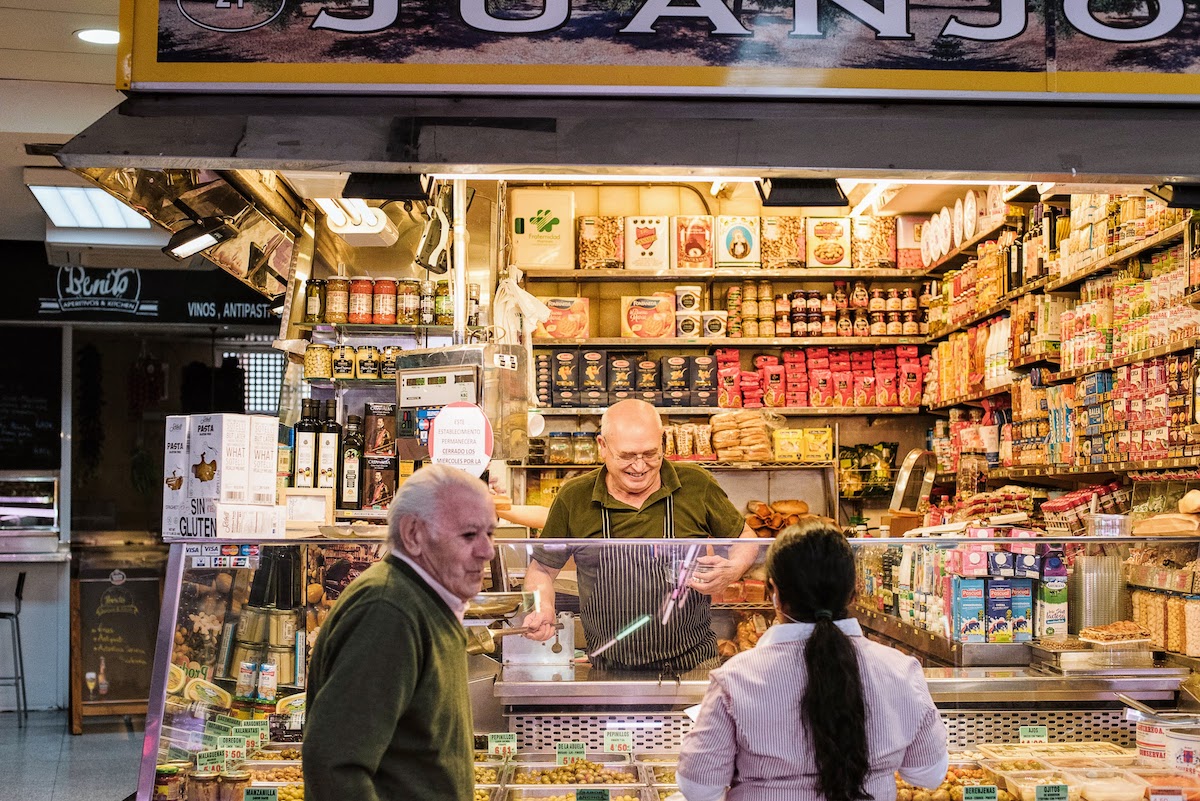 Un vendedor en un puesto del mercado sonriendo mientras atiende a los clientes.